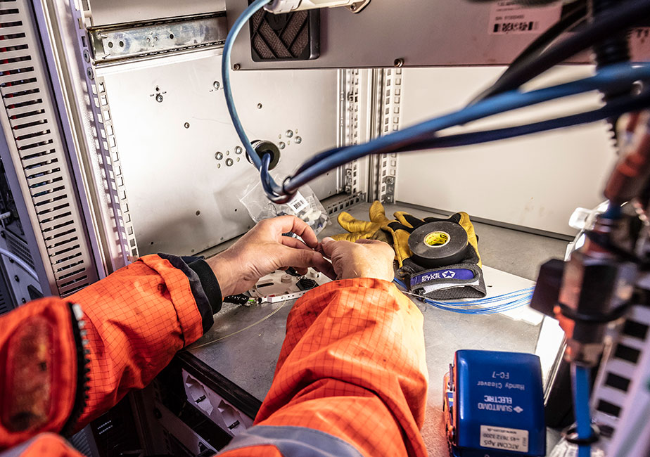 Certified technician connecting cables inside an industrial telecom control enclosure